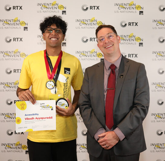Student at national convention holding winning medal and certificate standing next to ?