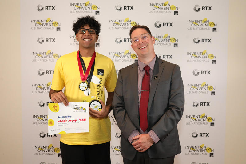 Student at national convention holding winning medal and certificate standing next to ?